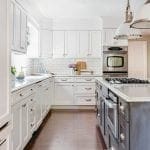 White kitchen with subway tile backsplash, marble countertops, and dark wood floors.