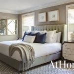 Bedroom with tufted headboard, gray upholstered bed frame, and decorative mirrors.