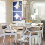 Dining room with round table, upholstered chairs, and abstract art.