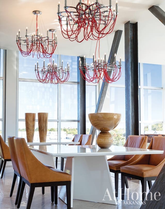 Dining room with white table, tan leather chairs, and red-corded chandeliers