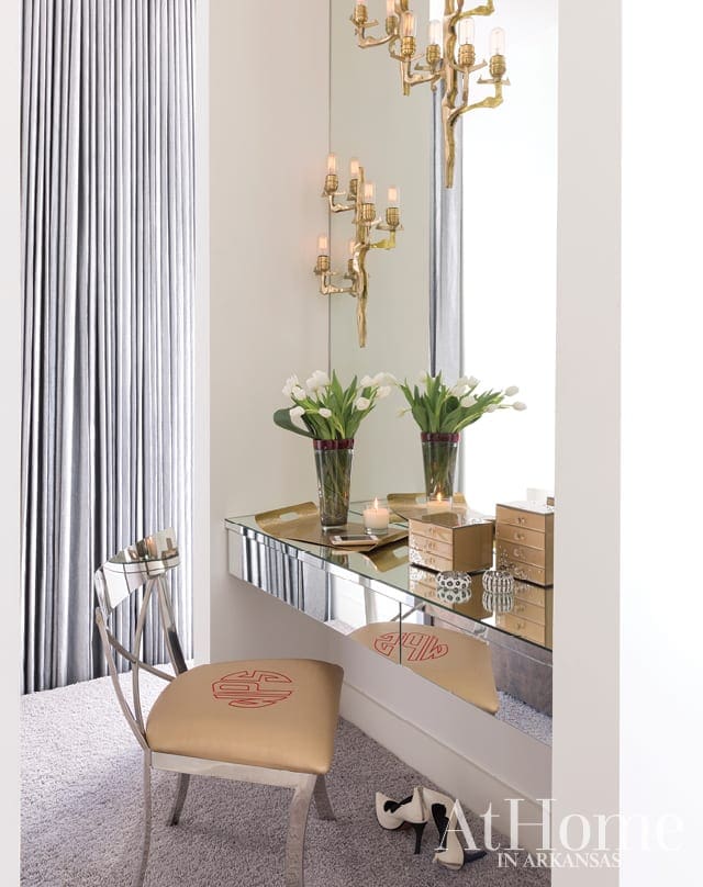 Vanity with mirrored surface, gold chair with red monogram, and white tulips