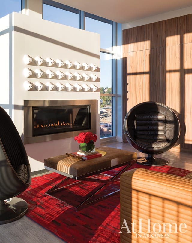 Living room with fireplace, modern chairs, coffee table, and red rug.