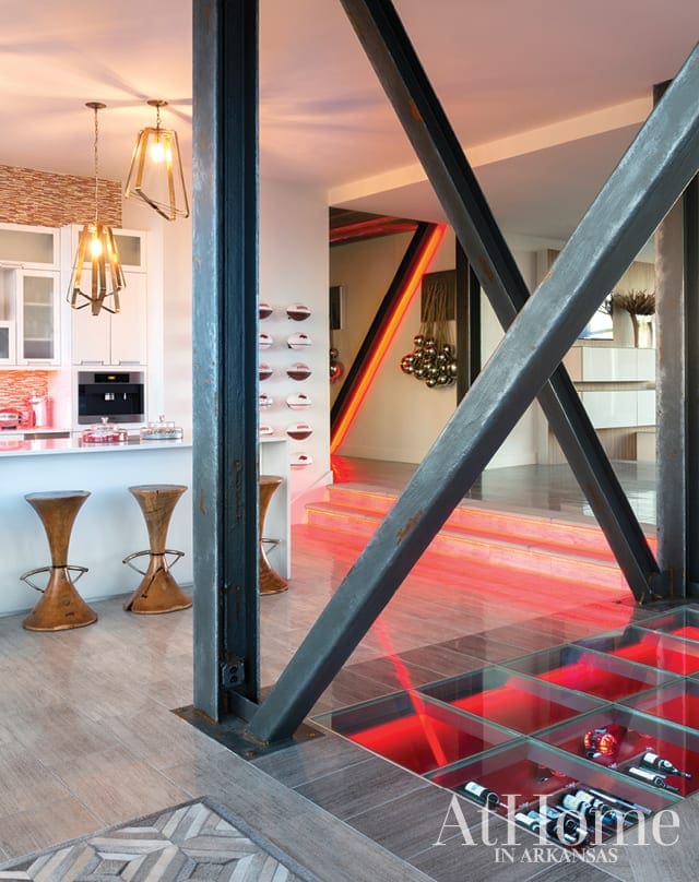 Modern kitchen with white cabinets and island, industrial metal beams, and glass floor with red