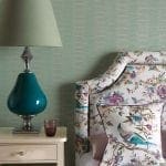 Bedroom with floral upholstered headboard, matching pillow, and teal glass lamp.