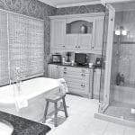 Bathroom with clawfoot tub, glass shower, and built-in cabinetry with patterned wallpaper