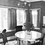 Dining room with round table, plaid curtains, and plant.