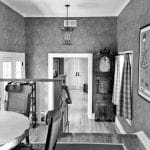 Hallway with grandfather clock, framed magazine cover, and staircase.