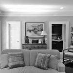 Living room with gray sofa, plaid pillows, and artwork above a dresser.