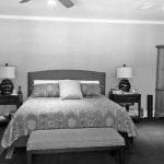 Bedroom with patterned duvet, upholstered headboard, two nightstands with lamps, and a tall wooden