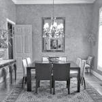 Dining room with dark wood table, upholstered chairs, ornate chandelier, and patterned rug.