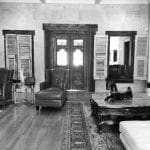 Living room with leather chairs, ornate wooden doors, marble-topped coffee table with horse