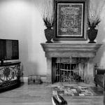 Living room with stone fireplace, framed artwork, vases, and wooden floors.