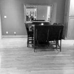 Dining area with dark chairs, table, and ornate mirror reflecting a person.
