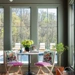 Sunroom with patterned chairs, marble table, and pool view