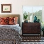 Bedroom with dark wood dresser, patterned rug, and framed art above bed.