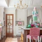 Kitchen with white cabinets, wood island, nutcracker decorations, and pink leopard print chairs.