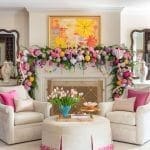 Living room with fireplace decorated for holidays, floral painting, and plush seating.