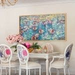 Dining room with floral upholstered chairs, white table, and water lily painting.