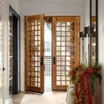 Entryway with double wooden doors, a large mirror, and holiday decorations.
