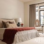 Bedroom with beige bedding, dark headboard, and window treatments.