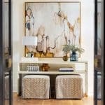 White console table with artwork, lamps, and seating.