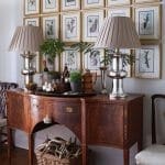 Dark wood console table with framed botanical prints and lamps.