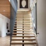 Wooden staircase with black metal railing and a large abstract sculpture.