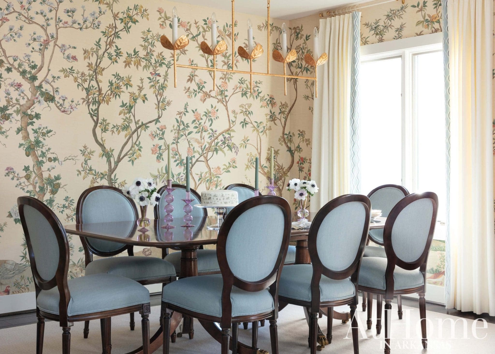 Gold sconces illuminate a blue dining table with chairs.