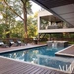 Wooden deck, pool, and outdoor seating area with a modern home.