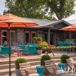 Red patio umbrellas and outdoor seating area with a stone house.