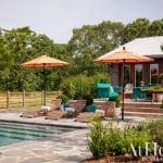 Outdoor patio with pool, orange umbrellas, and seating.