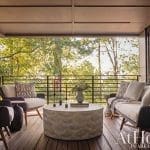 Outdoor seating area with a wooden deck, metal railing, and foliage.