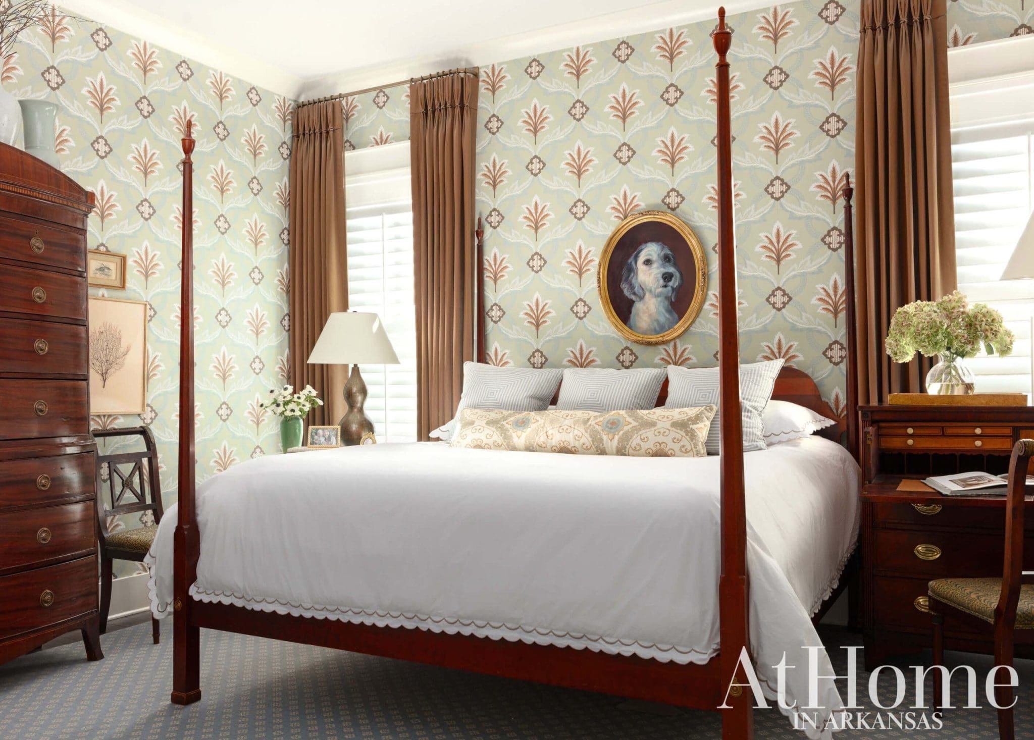 Blue and white wallpaper with a floral pattern, mahogany furniture, and a dog portrait.