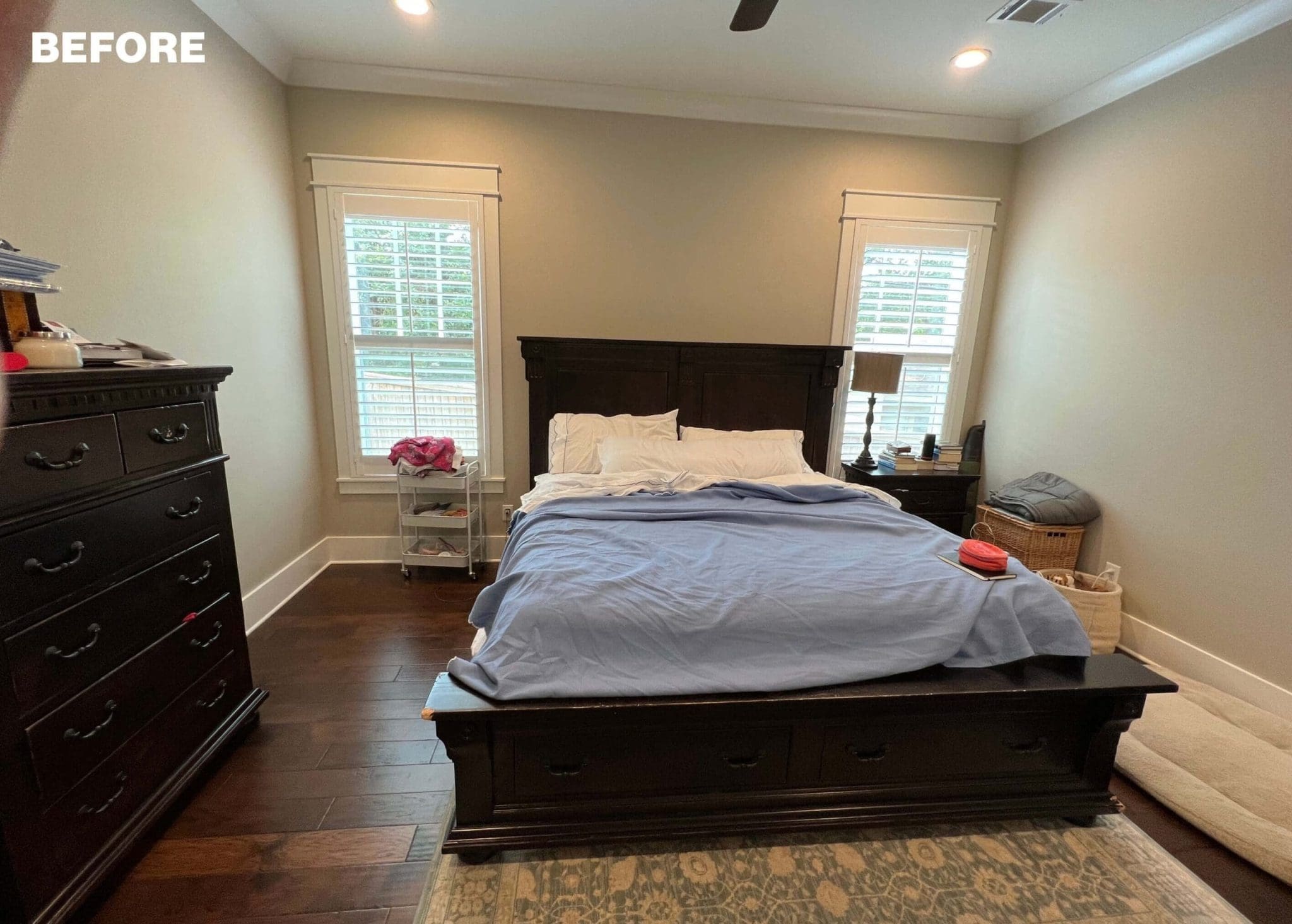 Dark bedroom with wooden floors, dresser, and bed.