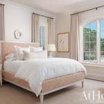 White bedroom with a tufted headboard, sheer curtains, and a window view.