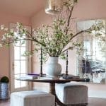 Round dining table with gray upholstered seating and a large floral arrangement.