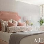 Pink upholstered bed with white bedding and pillows.