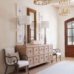 Wooden dresser with brass chandeliers and framed artwork.