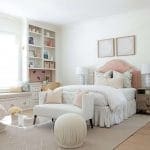 White bedroom with built-in shelving, bed, and rug.