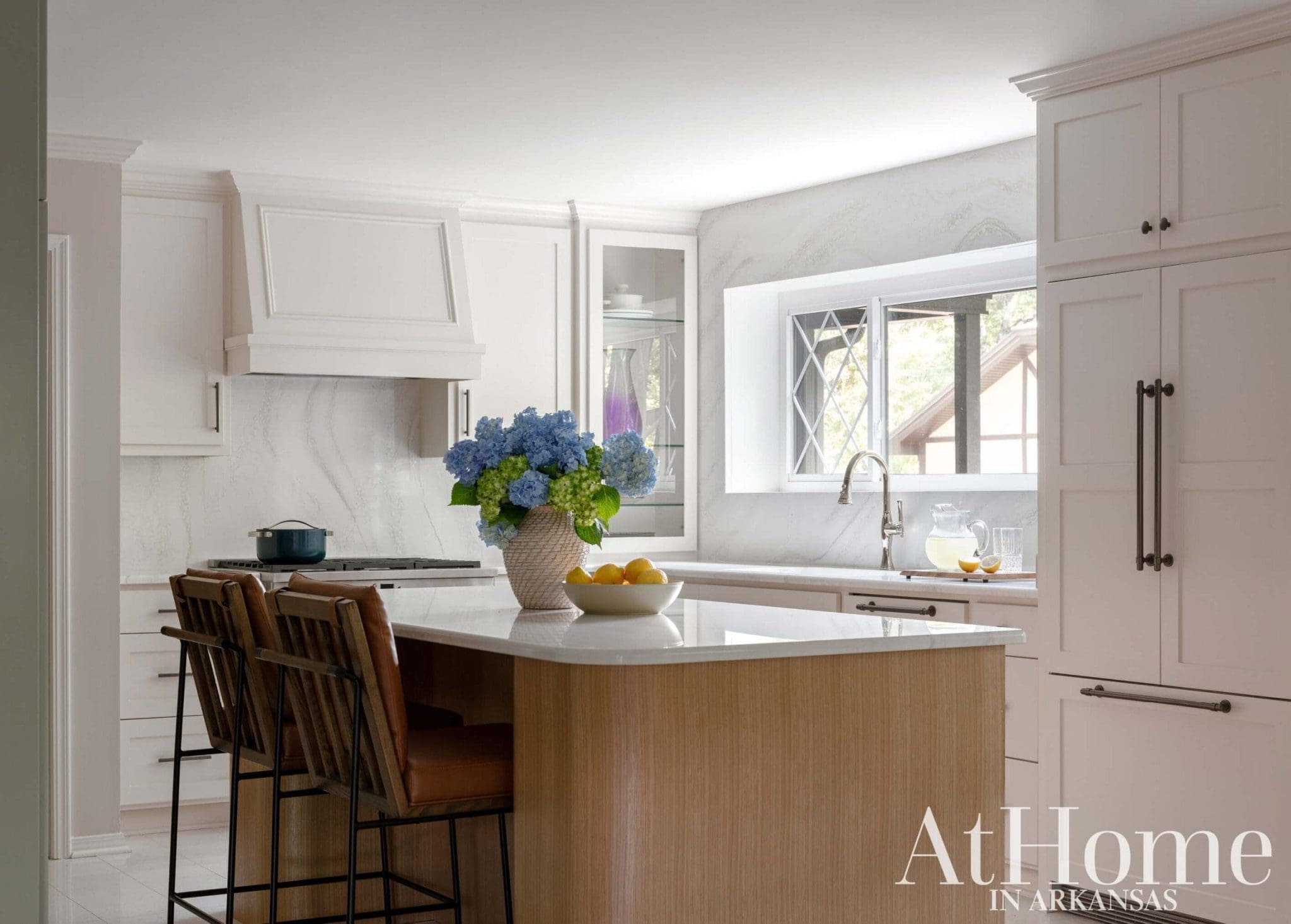 White kitchen island with wooden stools and a marble countertop.