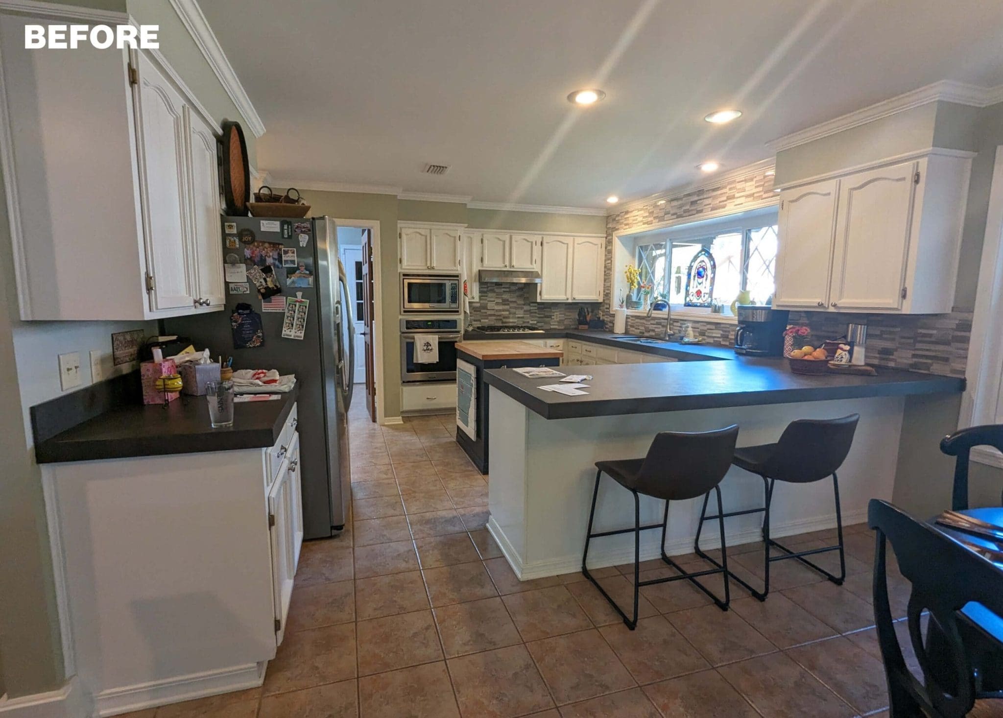 White kitchen with gray island and cabinets, tile flooring.
