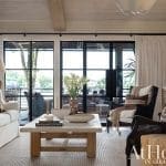 Living room with large windows, beige sofa, and a coffee table.