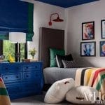 Blue-painted bedroom with patterned headboard and artwork.