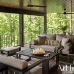 Outdoor seating area with sofa, table, and drinks on a wooden deck.