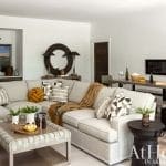 Gray sectional sofa with pillows, coffee table, and a round mirror.