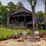 Dark gray house with a stone patio and outdoor seating.