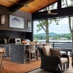 Outdoor kitchen with wood paneling, grill, and lake view.