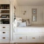 White built-in shelving unit with drawers and a bed.