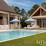 Exterior shot of a pool area with a large pool, patio, and umbrellas.