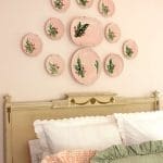 Pink plates adorn a pale green headboard with white bedding.